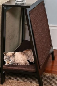 Wood side table with built-in cat cubby and scratcher panel, occupied by resting cat