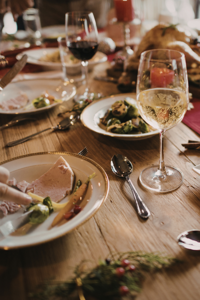 Holiday dinner table with wine glasses and festive food, showing a warm home environment that can feel overwhelming for cats during holiday gatherings.
