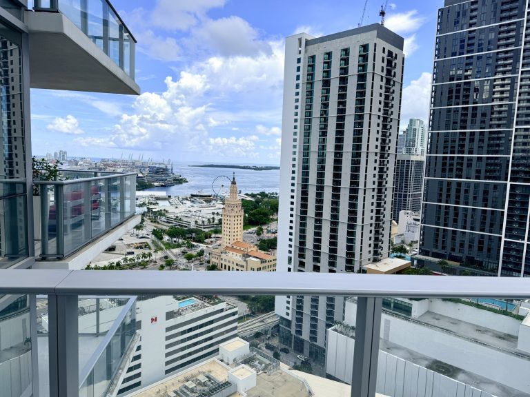 View from a high-rise balcony in Brickell overlooking downtown Miami, Biscayne Bay, and surrounding condominium towers.
