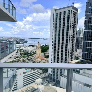 View from a high-rise balcony in Brickell overlooking downtown Miami, Biscayne Bay, and surrounding condominium towers.